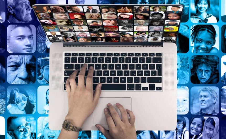 Person using a laptop. Faces of diverse people in the background